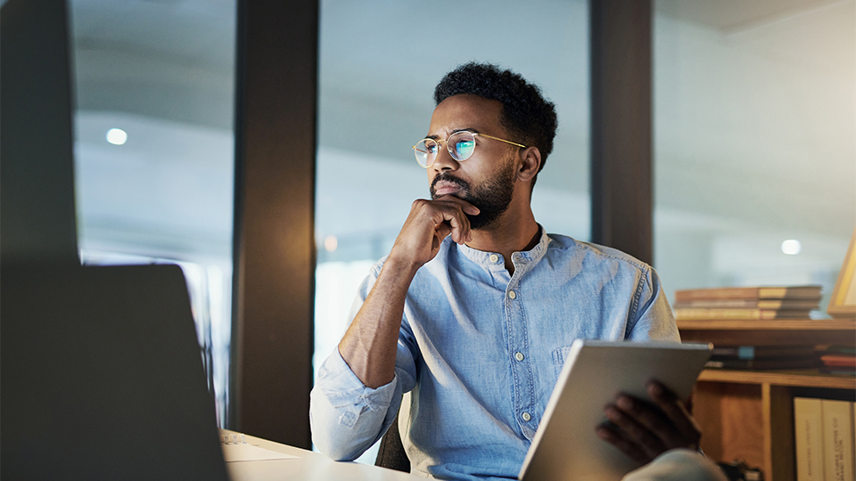 A man wearing glasses sitting at his desk