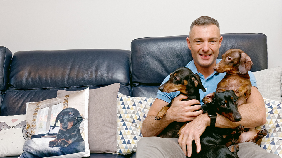 Optometrist Neil Retallic relaxes at home with his three dachshunds
