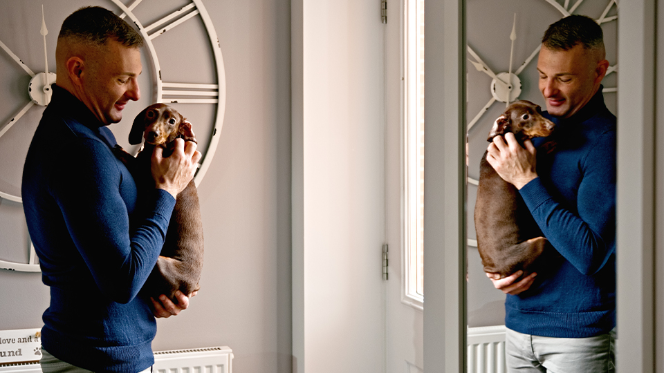 Optometrist Neil Retallic holds his dog in front of a mirror 