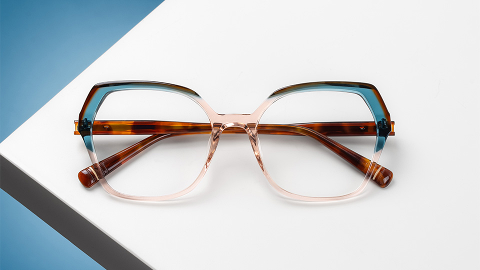An oversized, butterfly shape spectacle frame made with three different styles of acetate in Havana brown, light blue and transluscent pink