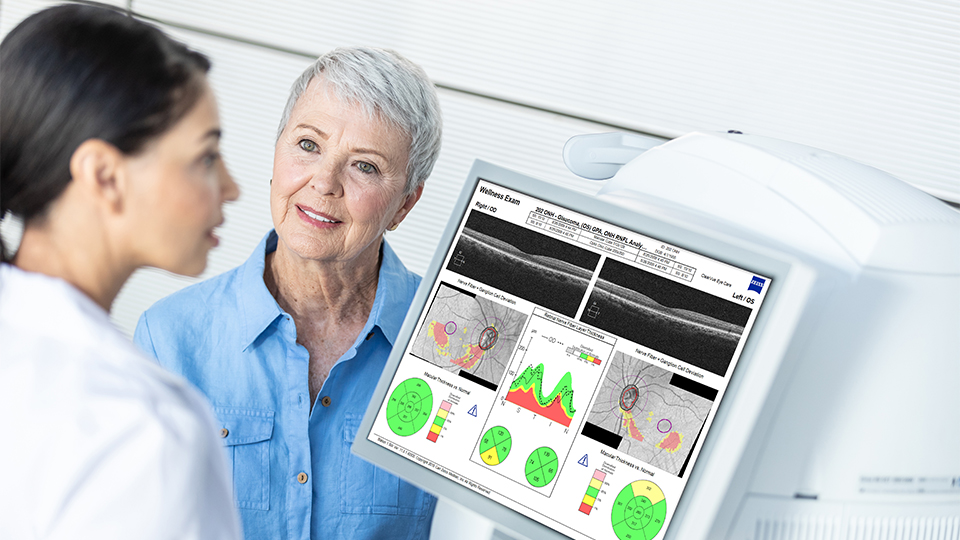An older woman has an eye test, on the device screen are various charts indicating eye health 