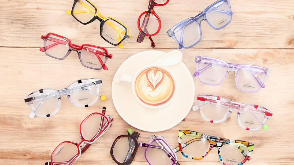 Colourful eyewear arranged around a coffee cup
