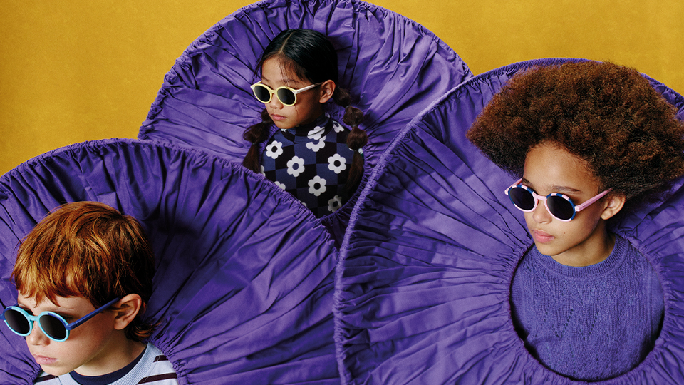 Three children wear giant purple ruffs and sunglasses