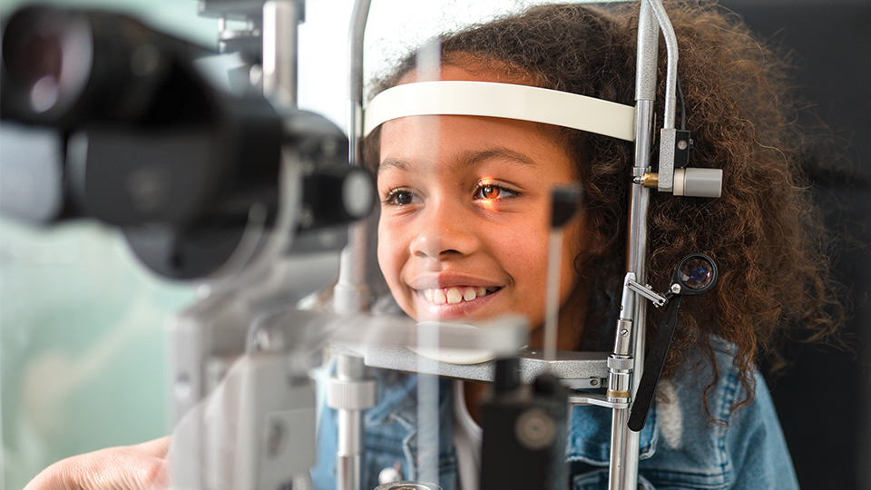 Young black girl smiling whilst having an eye test