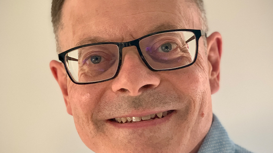 A close-up shot of Martyn Howlett, who is smiling in a grey shirt