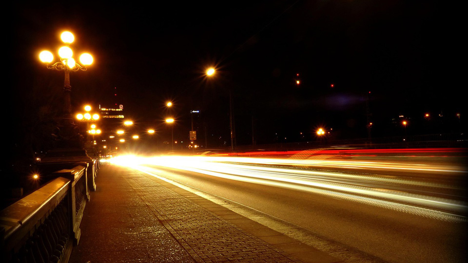 A road at night with headlights blurring into white and red streaks
