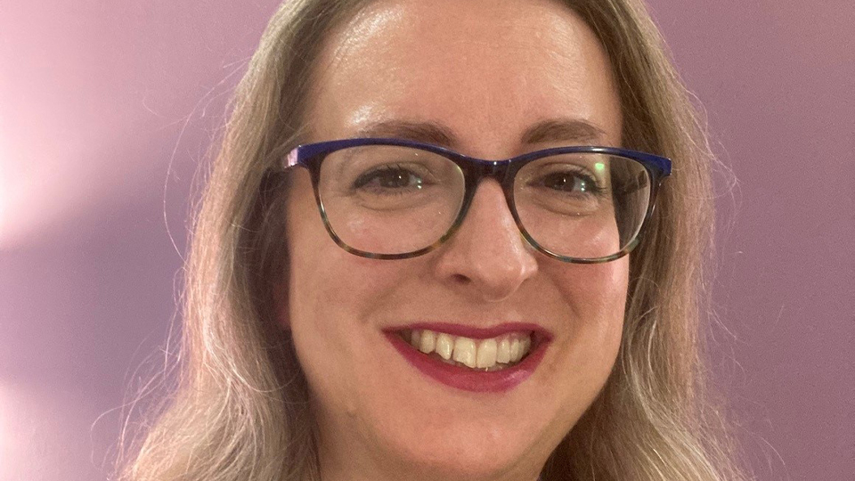 Amanda wears a dotty black shirt and purple spectacles