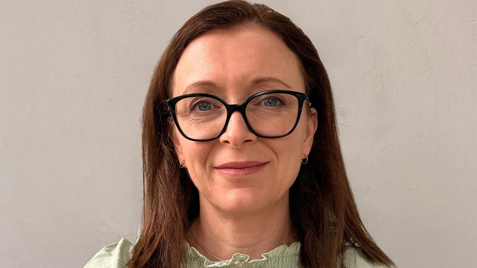 Catherine wears a ruched light green top and black cat’s eye style glasses