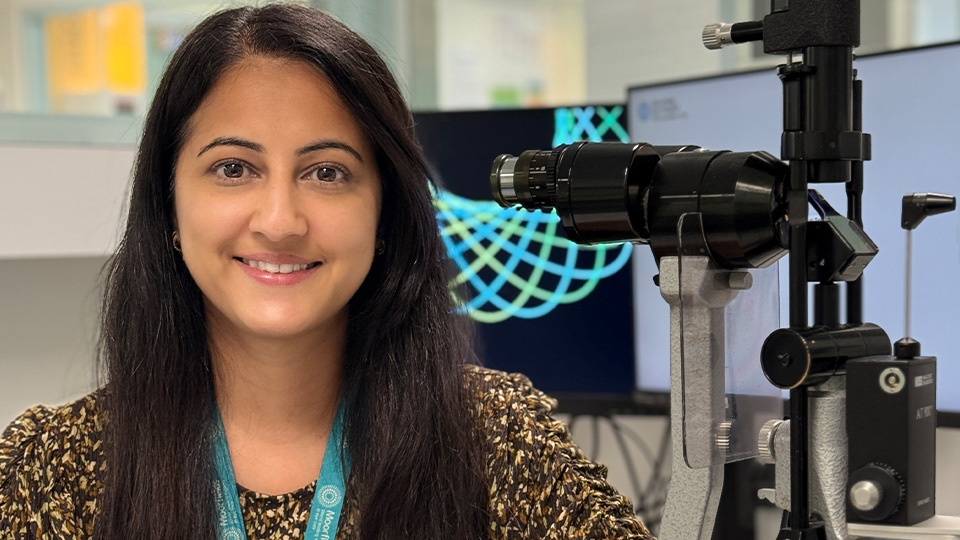 Simranjit smiles whilst sat at a desk
