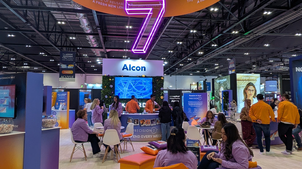 The Alcon stand at 100% Optical has a giant 7 written in neon signs from the ceiling and purple and orange seating