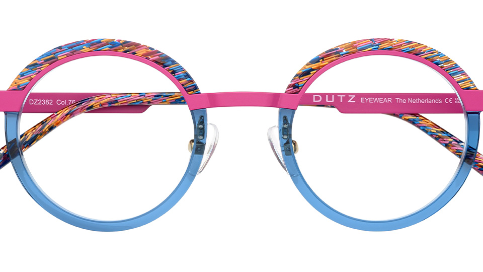 A pair of circle frames with multicoloured acetate top rim, nose bridge and temples in pink, and the bottom half of the rim in blue