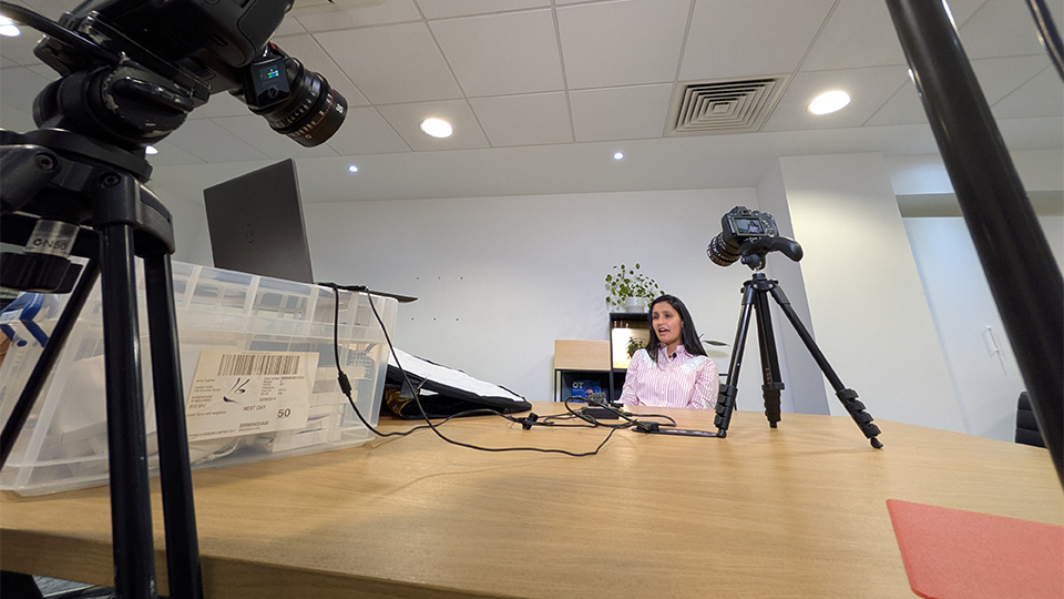 Farah Topia sitting at a table with a camera in shot