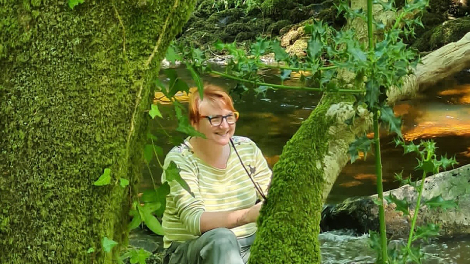 Sarah Gibson sat in a forest surrounded by greenery