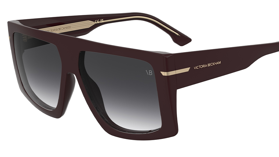 A pair of oversized burgundy sunglasses with a flat brow line. The temples include gold metallic detailing. The brand name, Victoria Beckham, is engraved in gold on the sides. The fashion house logo, VB is also engraved in the corner of the black ombre lens
