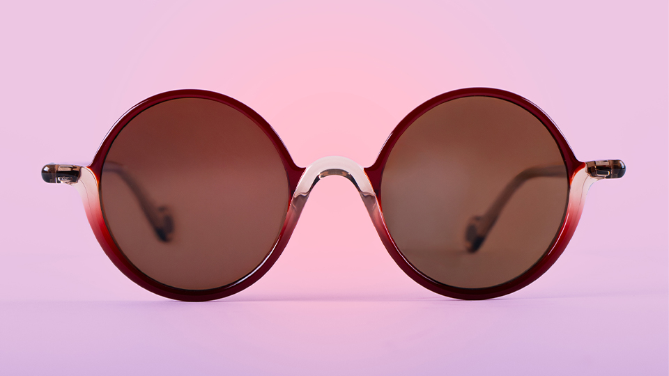 A pair of round frames with a darker red on the top half and a lighter gradient red-white on the bottom half. The bottom half of the frame is made from a thicker material, giving it a bottom-heavy and abstract look