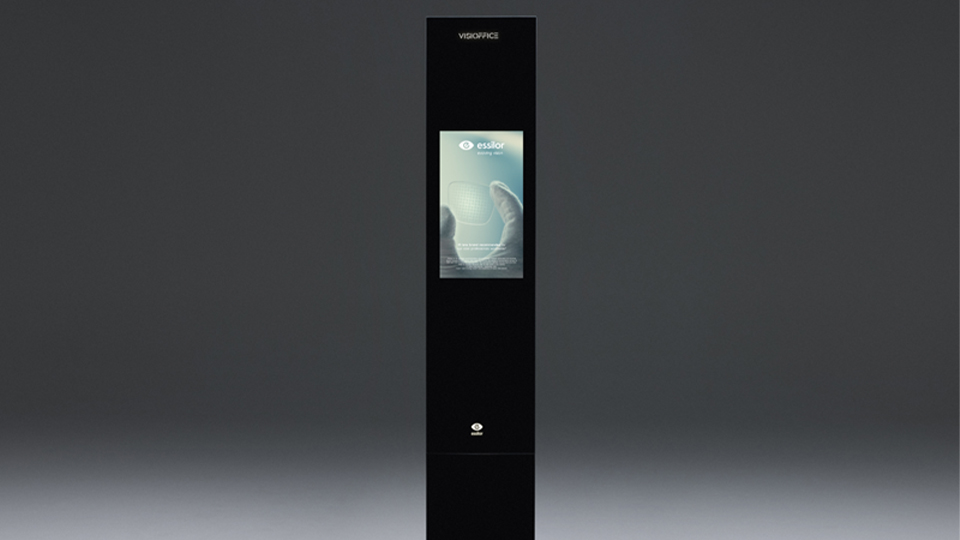 A large stand-alone rectangular mirror and screen. The device has a display in the centre showing an advert for Essilor lenses