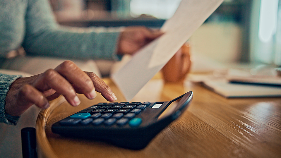 A woman uses a calculator while reviewing a document