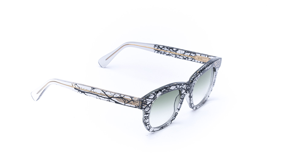 A pair of clear chunky cellulose acetate frames with trailing plant fibres set into the material, creating an effect similar to growing roots