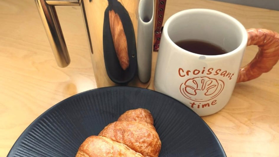 A coffee and a croissant on a tabletop