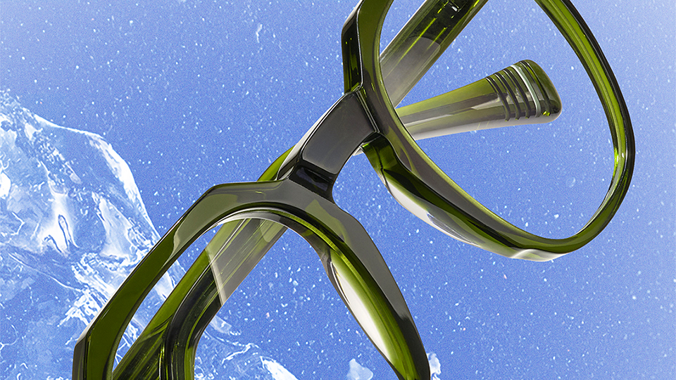 A pair of green acetate frames with a geometric frame top, positioned on a light blue background with ice positioned behind