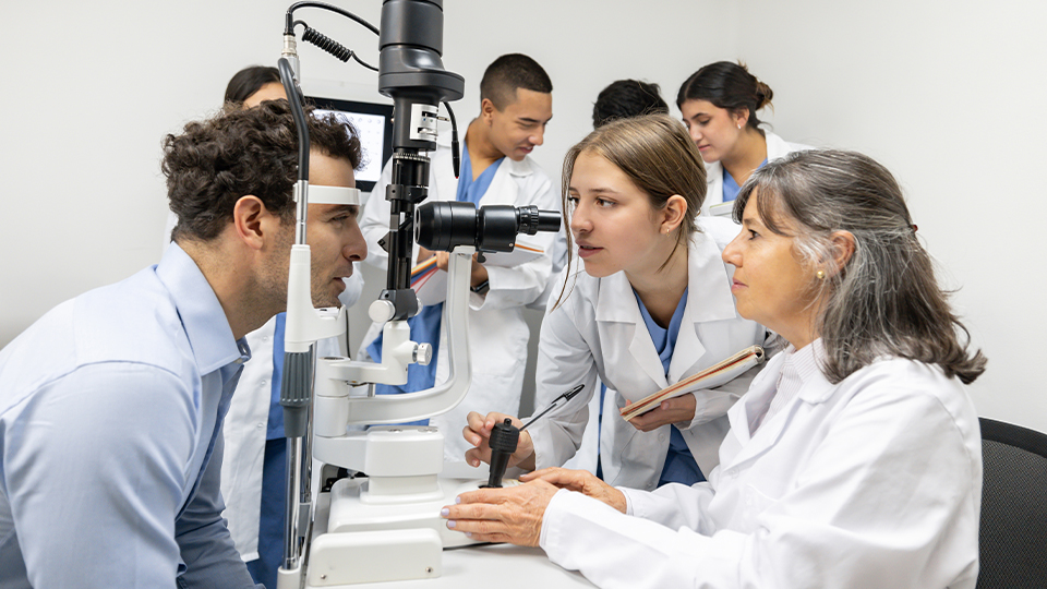 Optometry teacher teaching students how to perform an eye exam using an eye test equipment