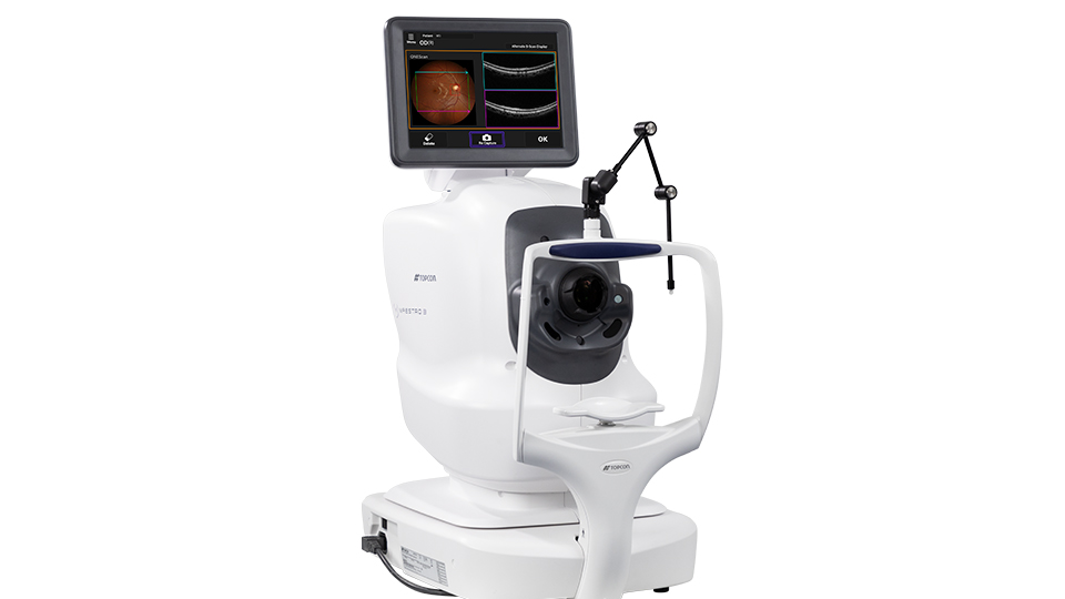 A white OCT device, positioned with the headpiece and scanner forward and a screen displaying the scan of an eye
