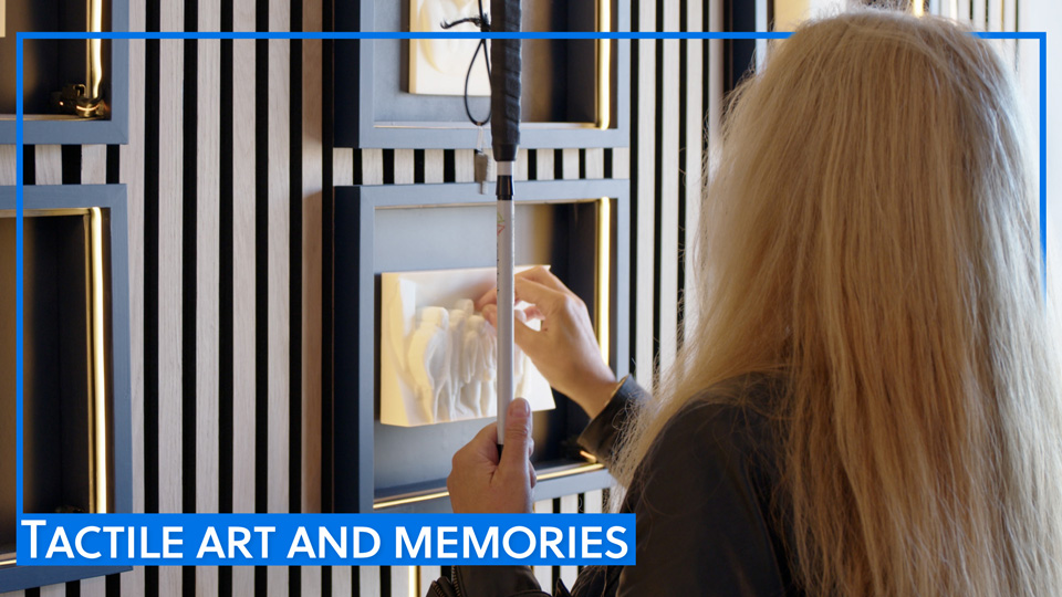 An exhibition attendee touches a 3D tactile artwork
