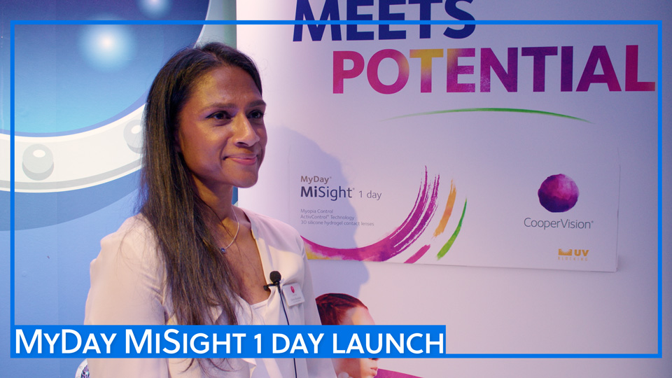 Chithra Dhanablan stands near a banner for CooperVision’s new contact lens – an image of the new packaging is displayed in large scale. Behind her the walls are decorated like a submarine