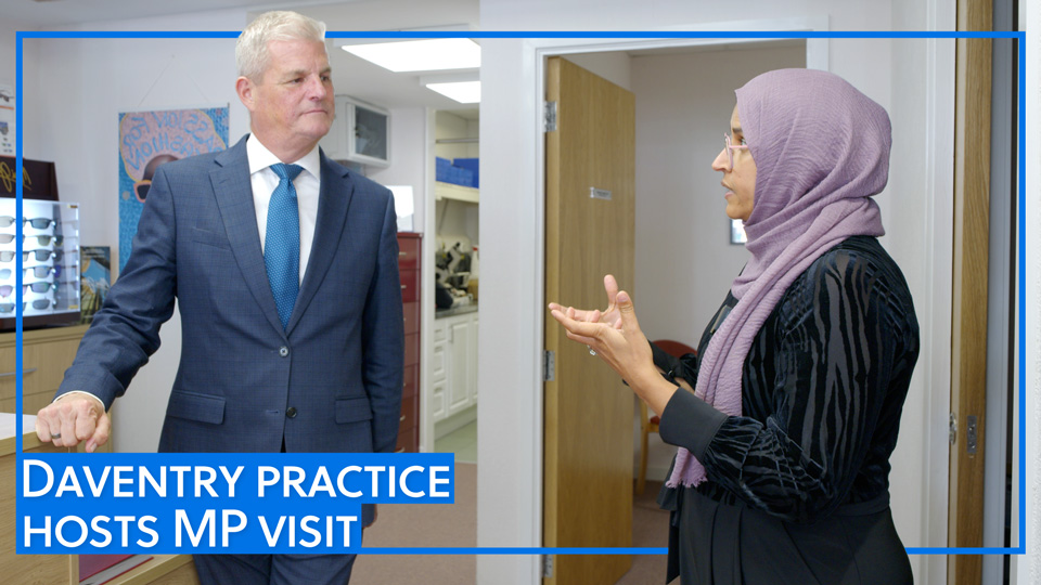 A practitioner is talking expressively to an MP during a visit to an optometry practice