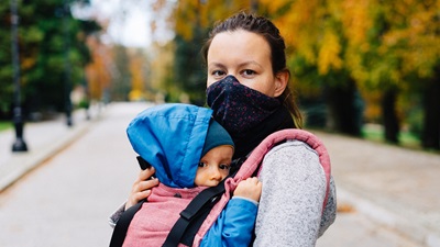woman wearing face mask holding a child