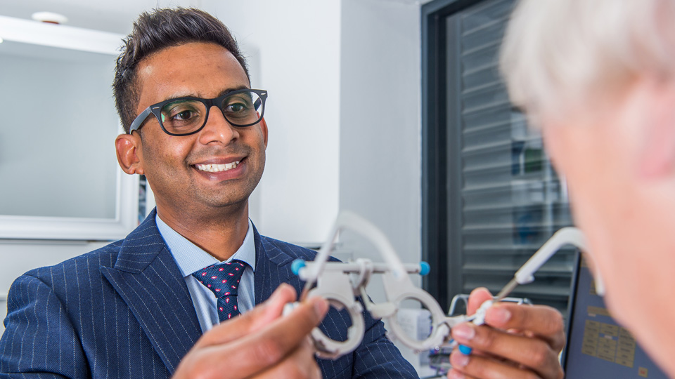 Harjinder is holding out trial frames to a patient