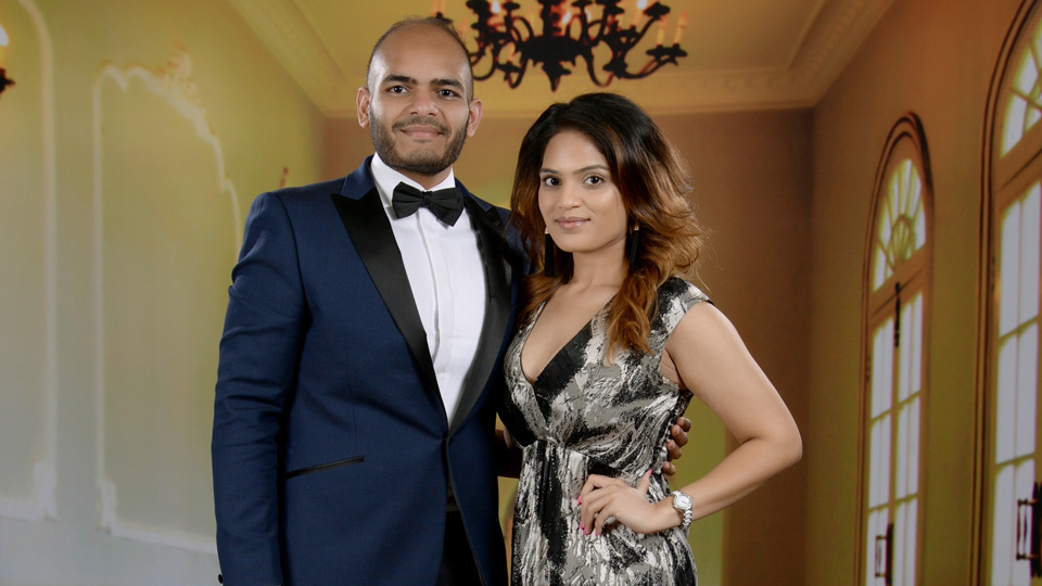 Bhavi and Mishaal, dressed in black-tie attire, stand together in a grand hall