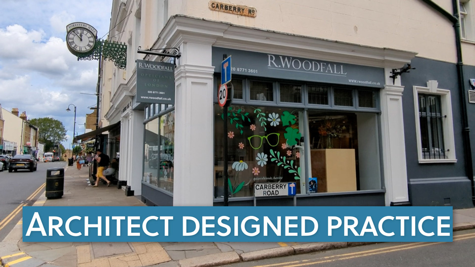The exterior of an optical practice on a cloudy day shows grey signage and a painted illustration of flowers in the window