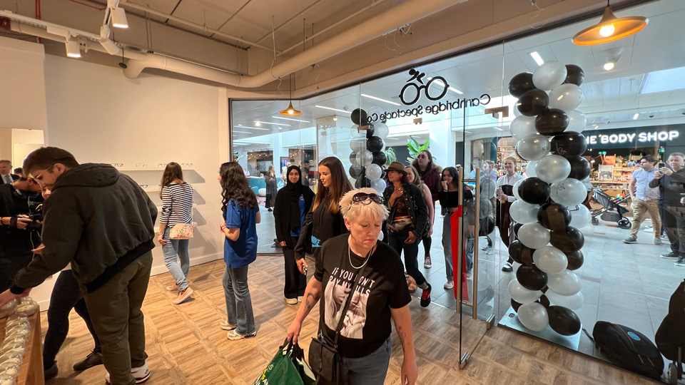 A group of people walk through the doors of the officially-opened Cambridge Spectacle Co., looking around at the frames on display