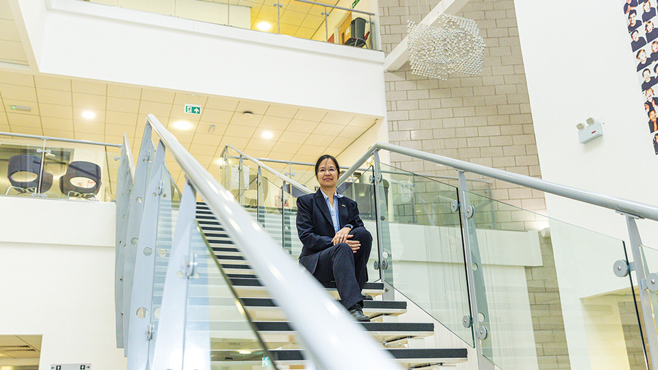 Joy sitting in the middle of a flight of stairs inside a modern building