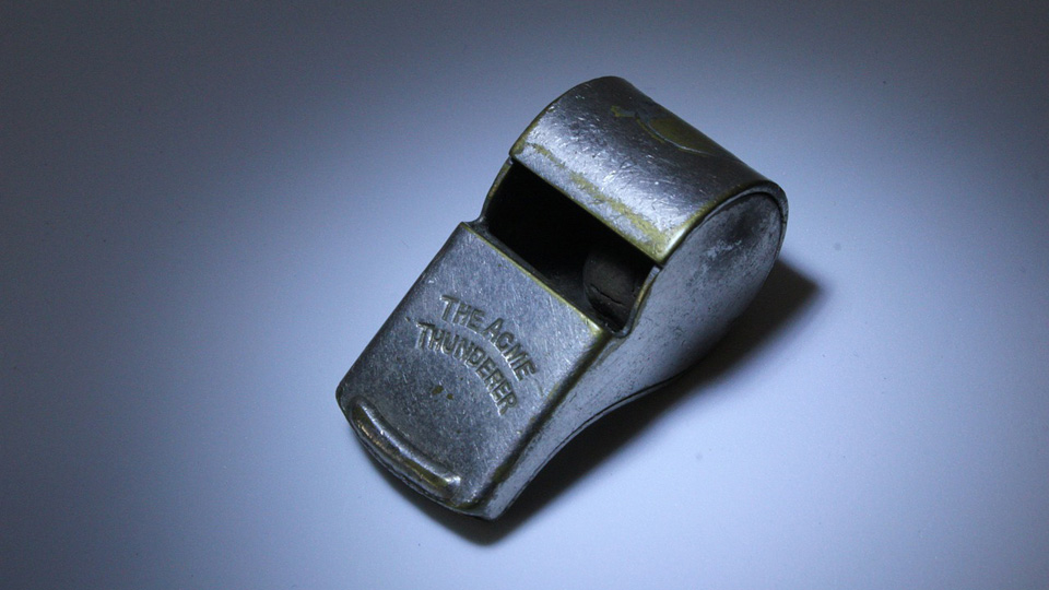 A metal whistle is displayed on a plain background