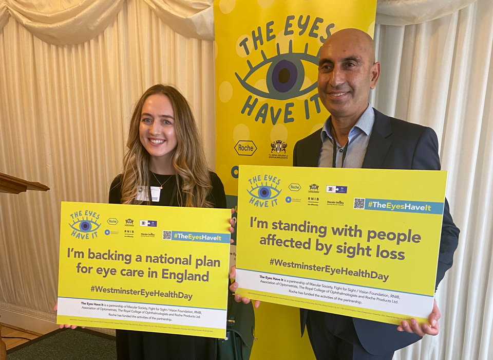 A female and male optometrist both holding yellow campaign posters from The Eyes Have It campaign