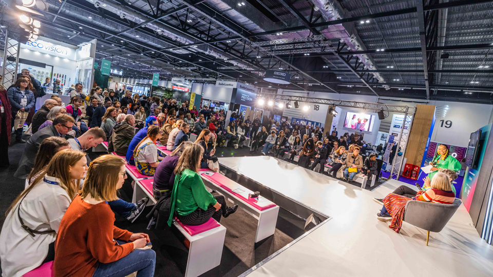 The catwalk stage at 100% Optical. A large audience surrounds the catwalk shaped stage. 