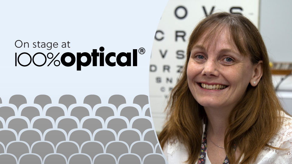 Sitting in a practice room in front of a Snellen chart, Louise Gow wears a floral white blouse and smiles warmly