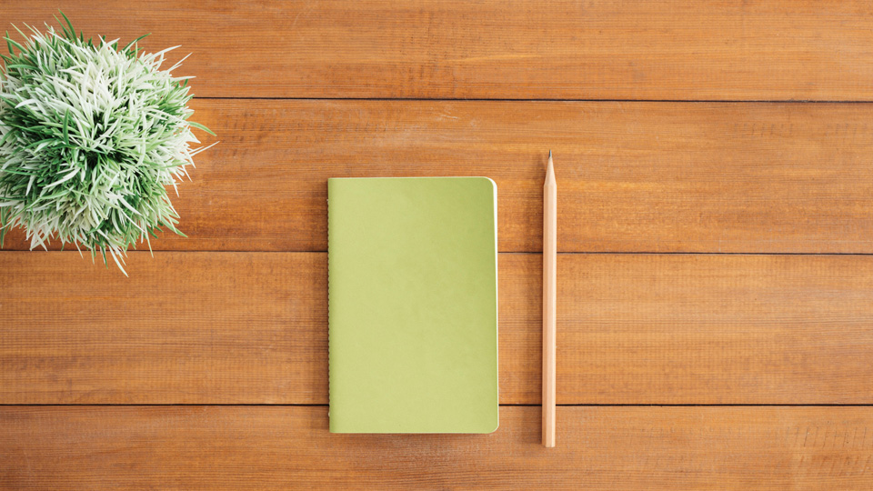 A notebook on a plain wooden desk 