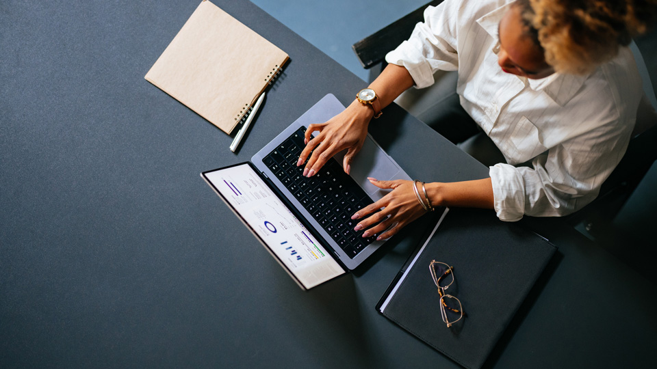 High angle view of a woman typing on a laptop keyboard on a grey table 