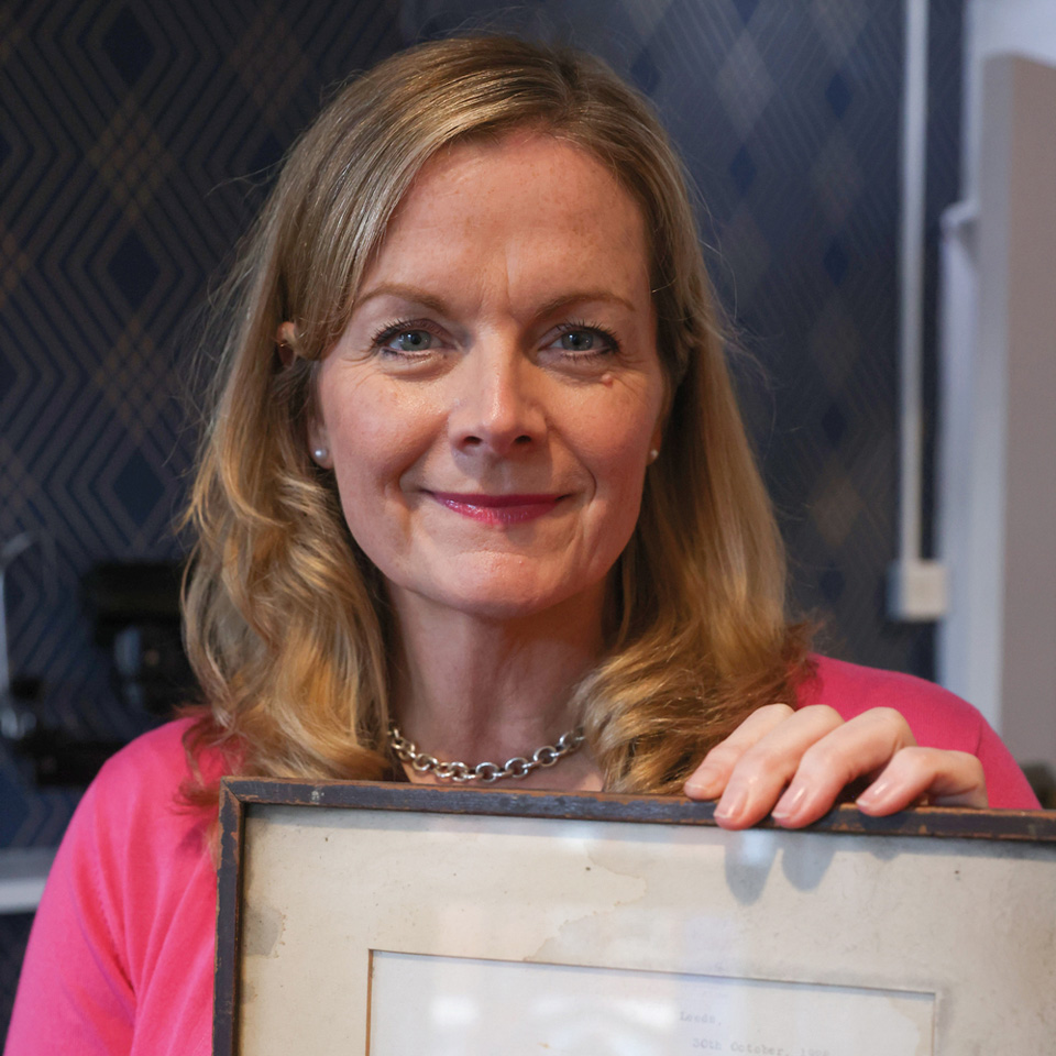 A woman with blonde hair holding a framed letter