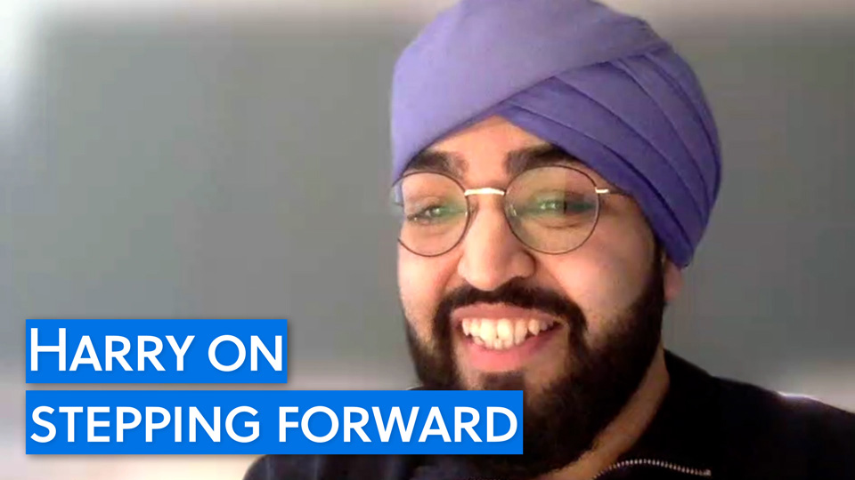 A man in spectacles with a beard and purple turban smiles at the camera. On the screen, the text ‘Harry on stepping forward’ is displayed 