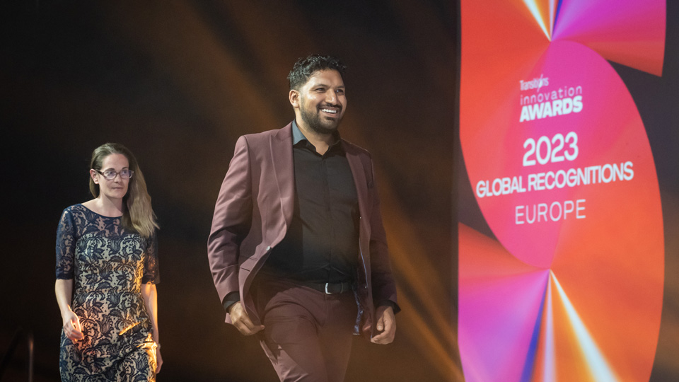 Zabir Ali walking across the stage on the way to collect his EMEA recognition award during the Transitions Innovation Awards