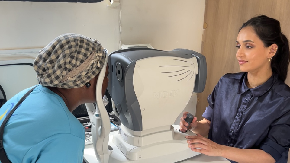 Amina is in a testing room sat opposite a patient at a table 