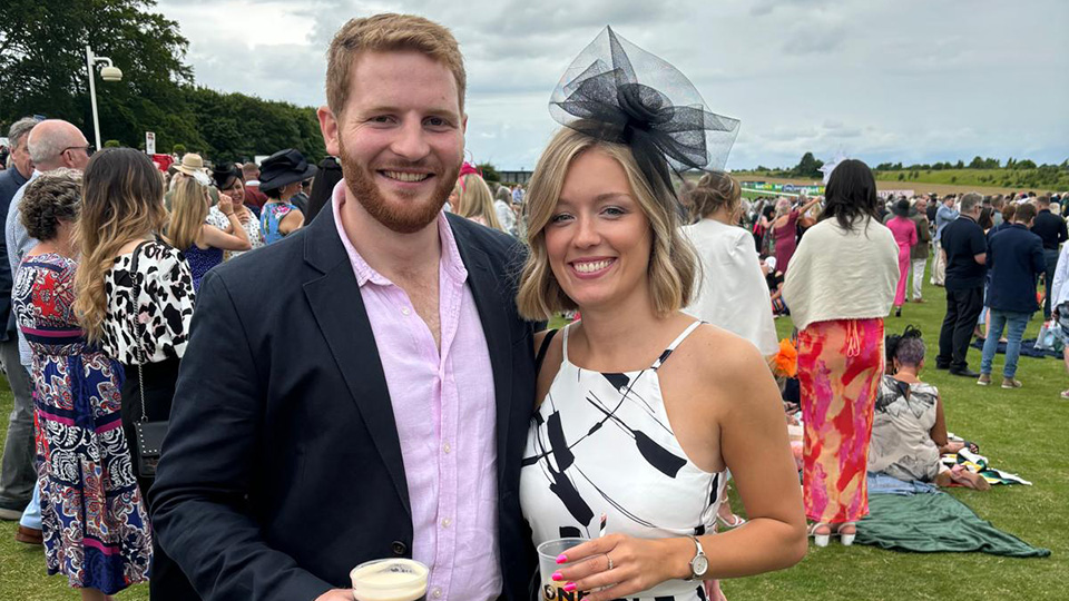 Hugo stands with his girlfriend, Francesca, both dressed smartly for an event