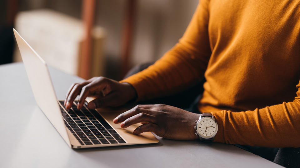 A man is seated at a coffee table working on a laptop 