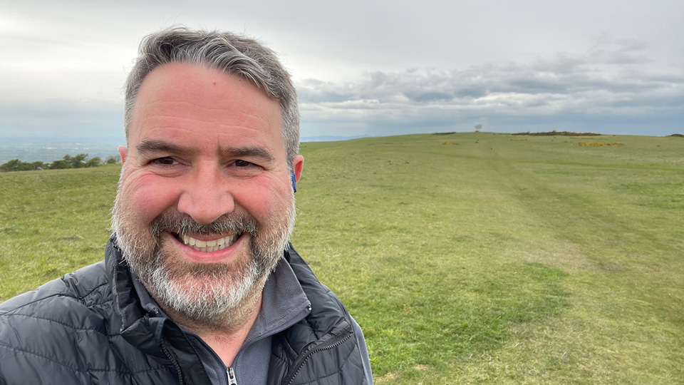 Man with a grey beard and hair smiling