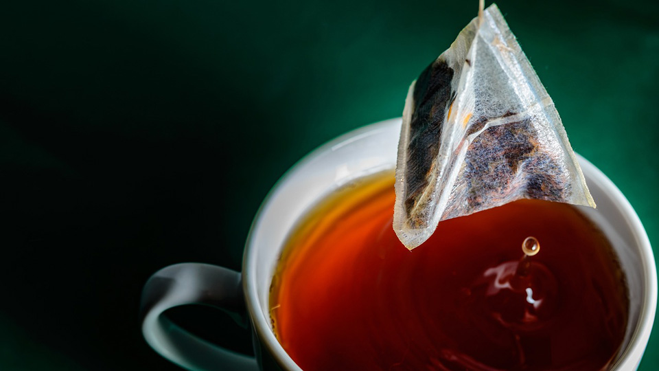 A tea bag is lifted from a cup 