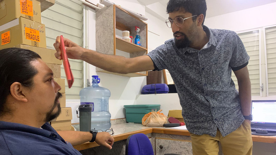Chandra is in a testing room, leaning forwards towards a patient 